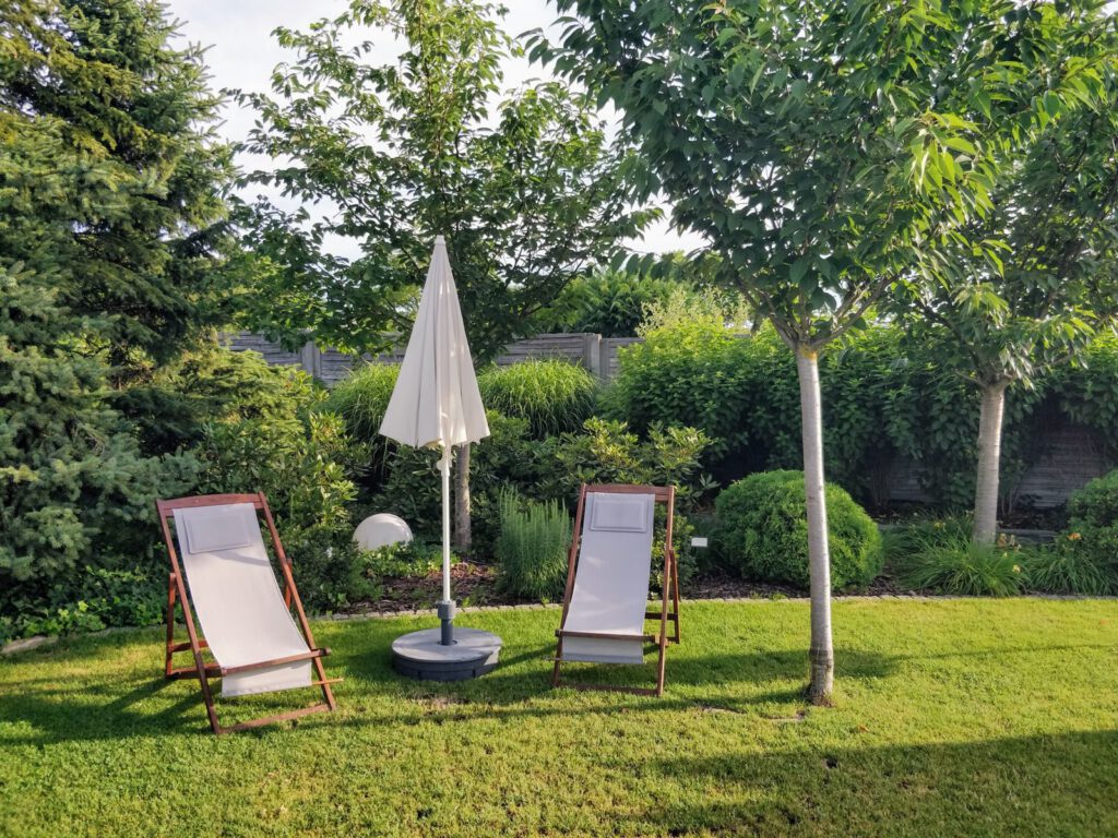 Peaceful garden setting with two loungers under trees, ideal for outdoor relaxation.