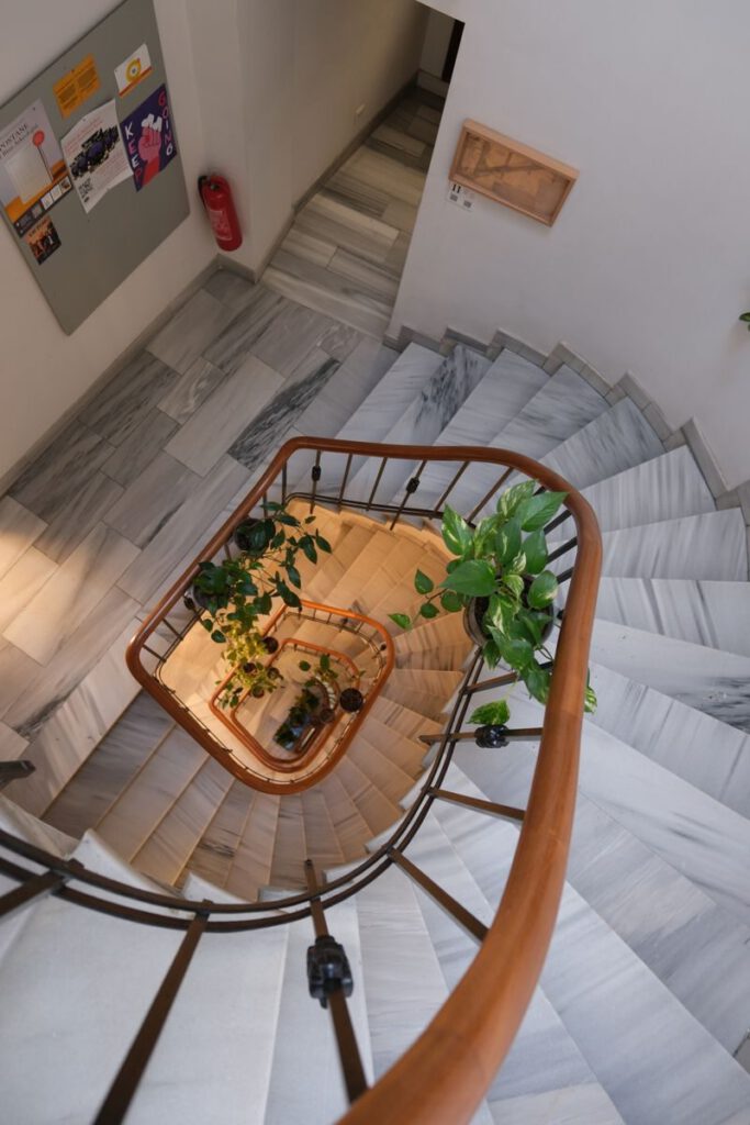 Top view of a marble spiral staircase adorned with plants, creating a serene indoor atmosphere.